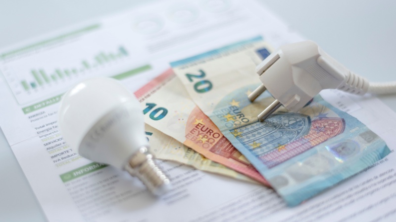 Bolletta con lampadina e spina sopra a banconote